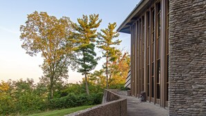 A building with a stone facade, large windows, and a stone retaining wall.