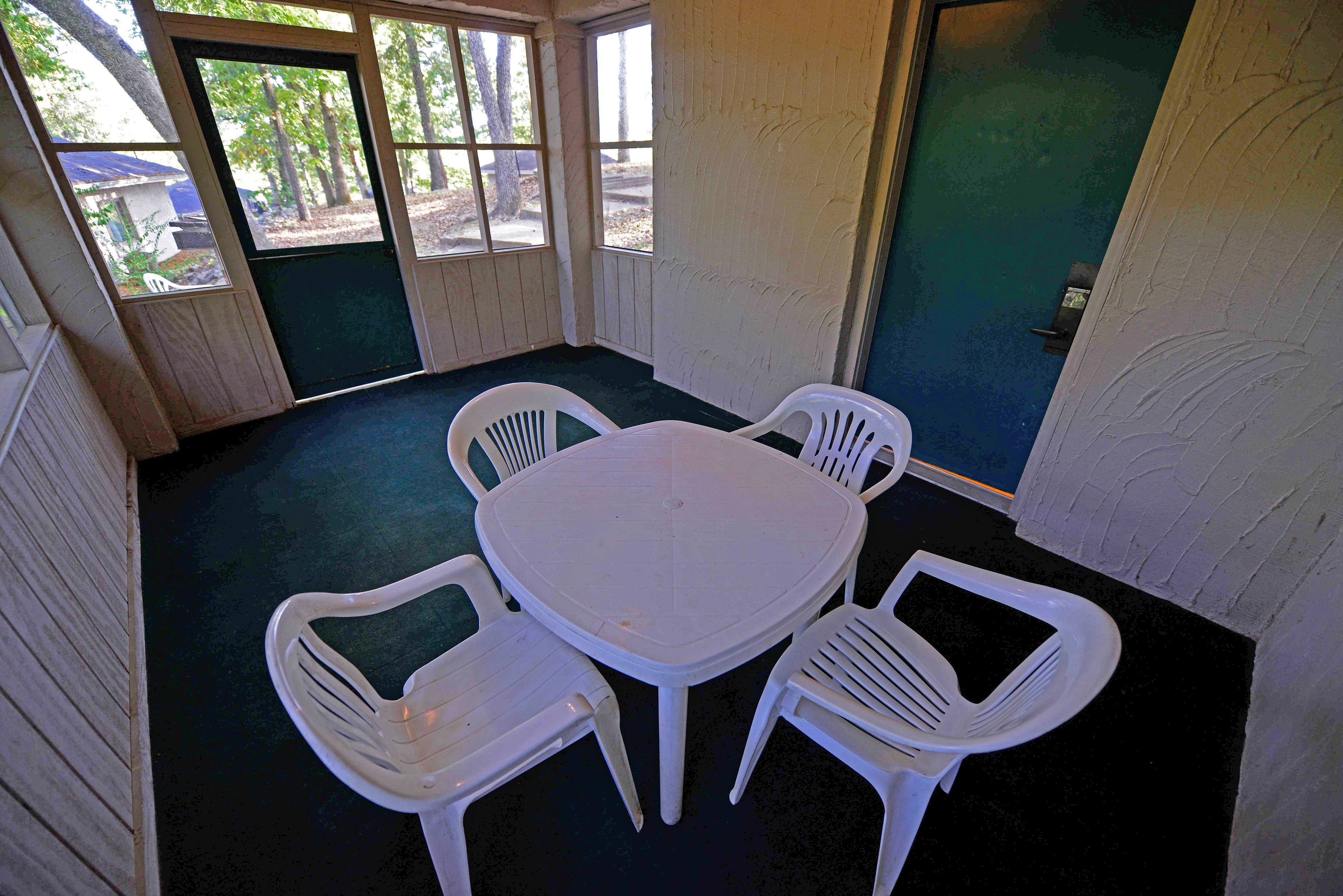 A room with a round table and four white plastic chairs.