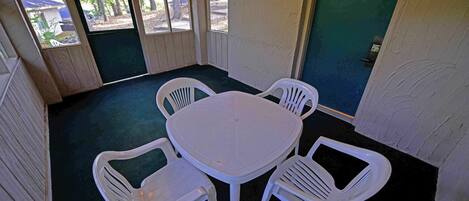 A room with a round table and four white plastic chairs.