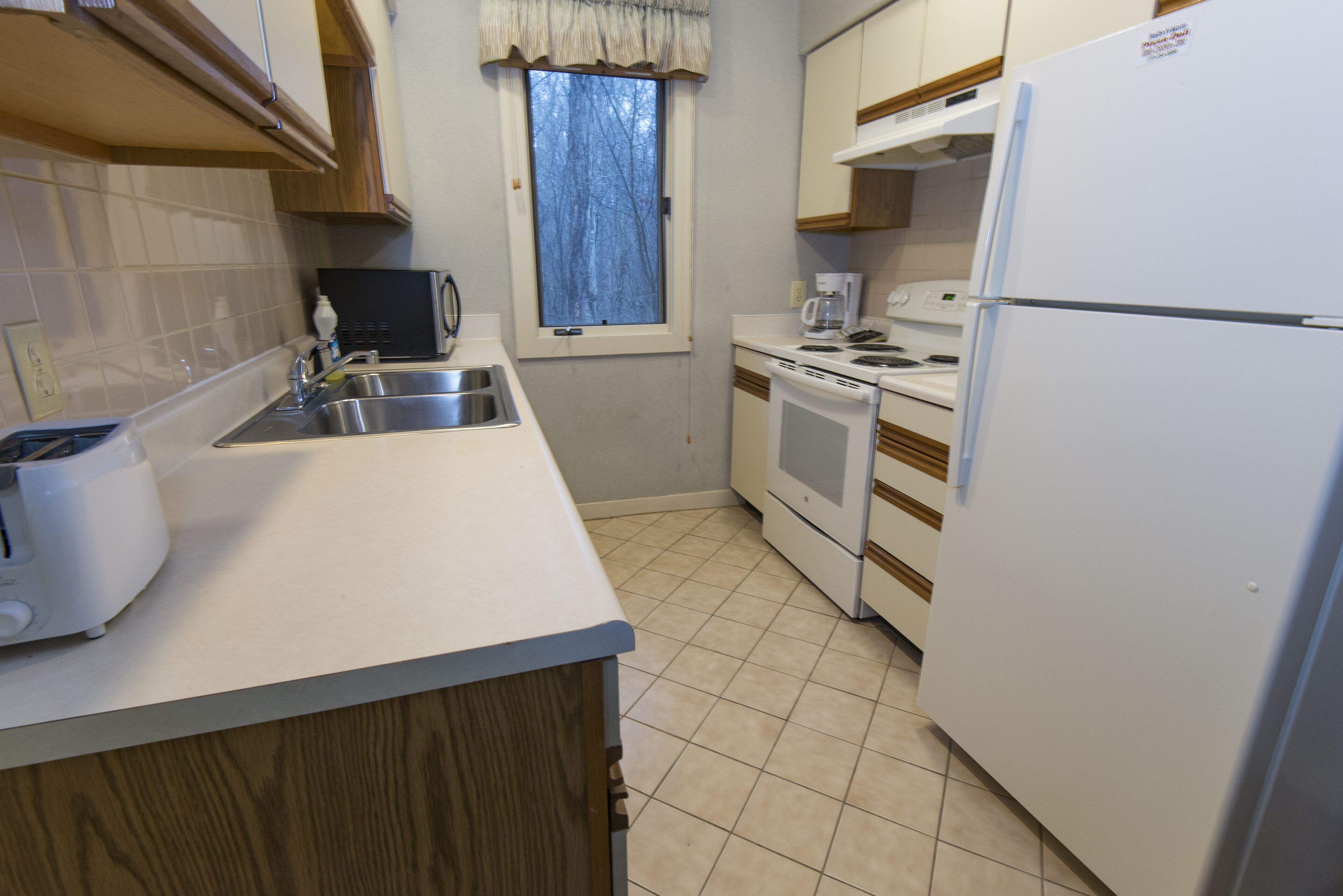 A compact kitchen with a sink, stove, microwave, and refrigerator.