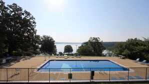 A swimming pool with a view of a lake, surrounded by trees and a fenced area with lounge chairs. - Kenlake State Resort Park (Hardin)