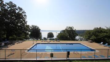 Relax by the pool surrounded by lush greenery and a serene lake view.
