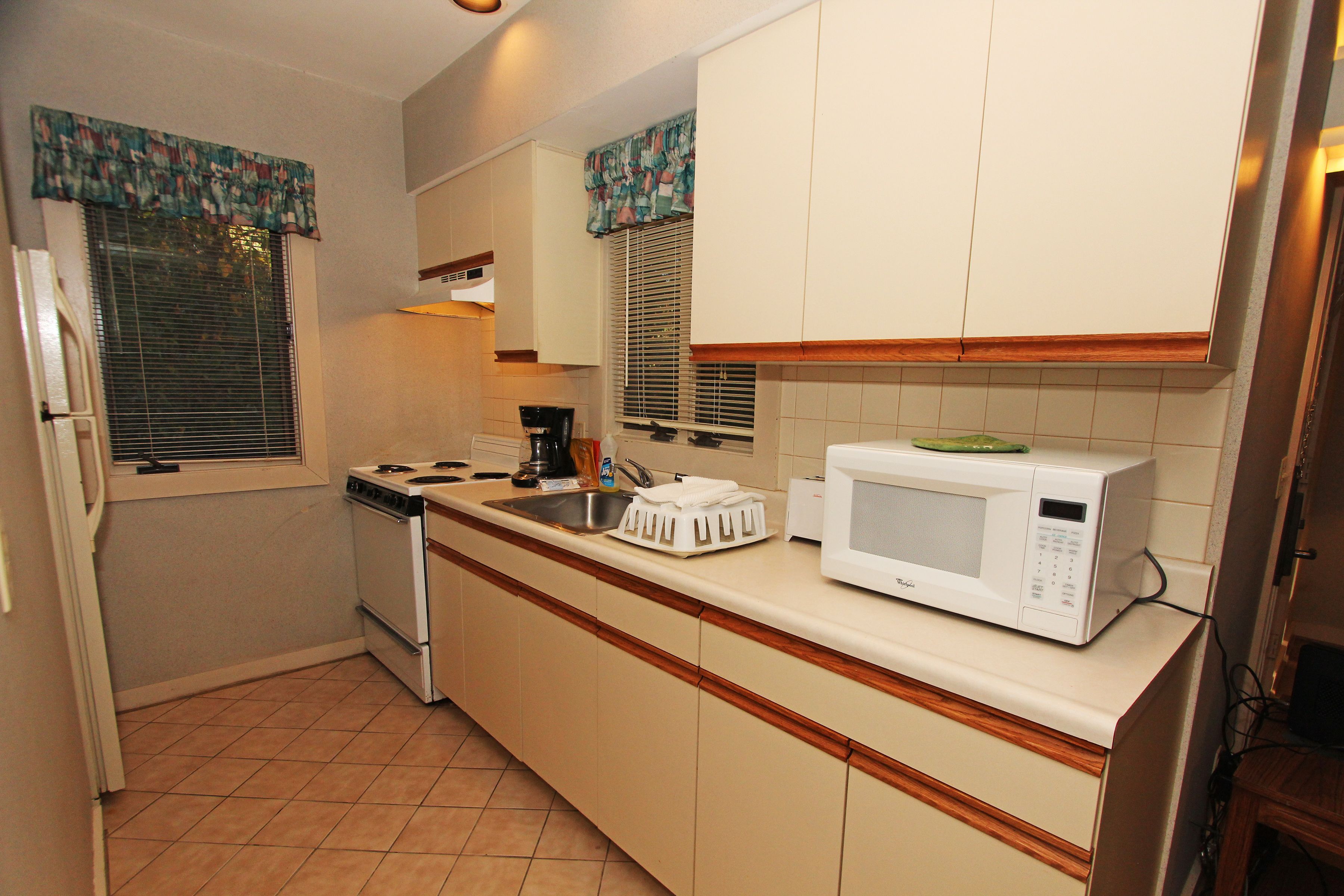 A small kitchen with a stove, sink, and microwave.