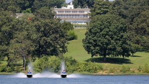 A lake with two watercraft creating a wake. In the background, there is a large building surrounded by trees. - Kenlake State Resort Park (Hardin)