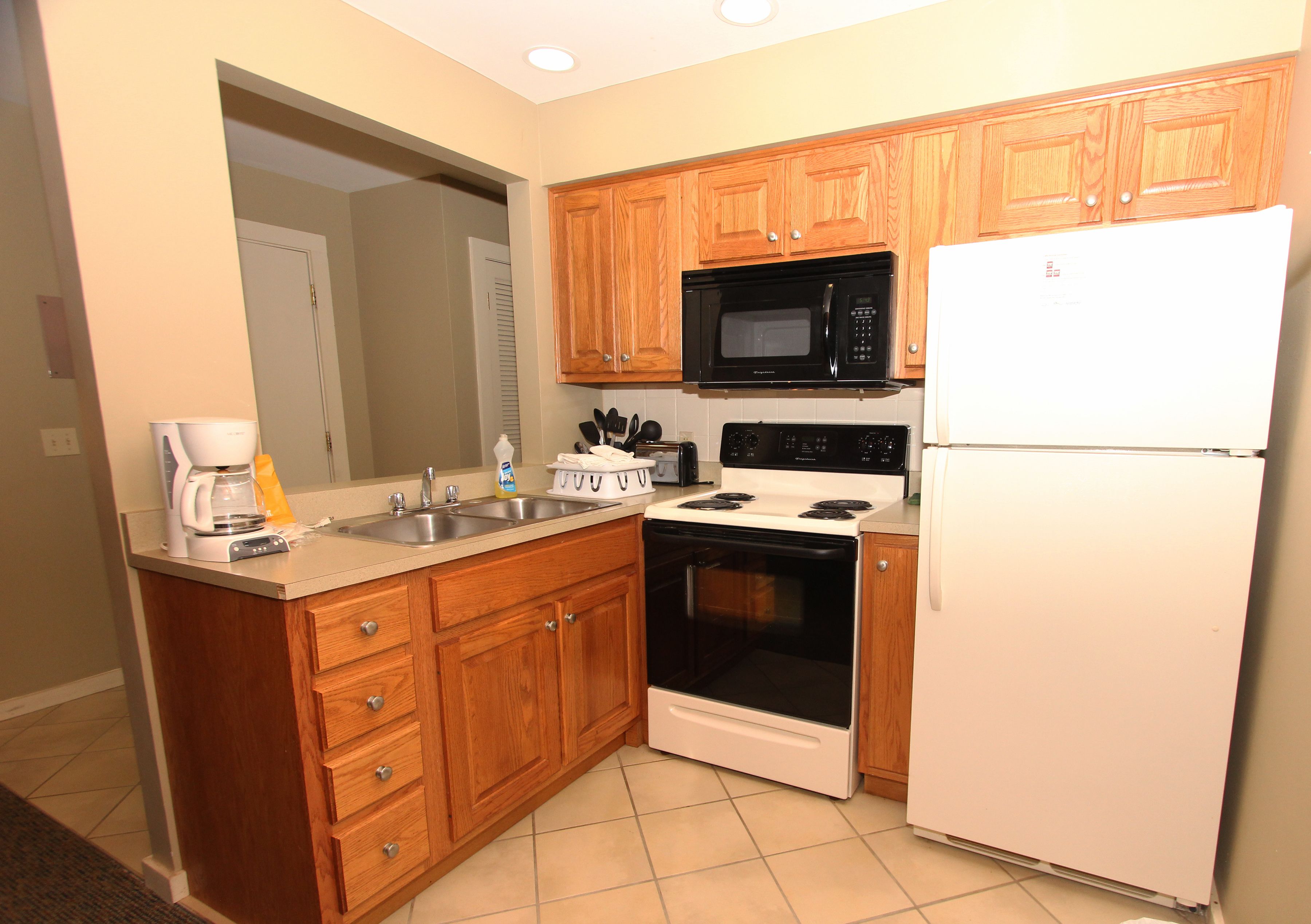 A kitchen with wooden cabinets, a microwave, a stove, and a refrigerator.