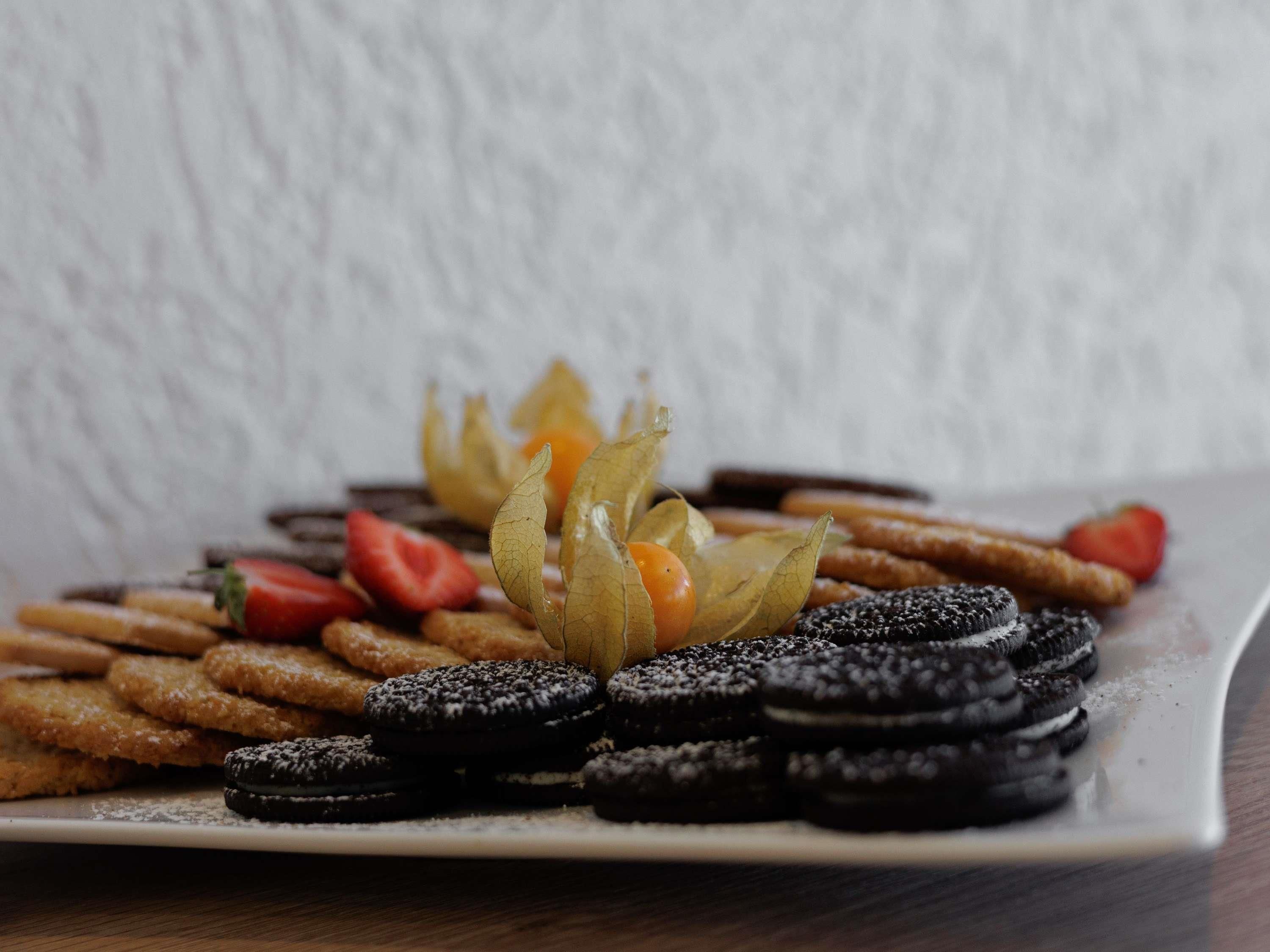 A plate of cookies, strawberries, and a decorative arrangement of leaves.