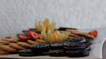 A plate of cookies, strawberries, and a decorative arrangement of leaves.