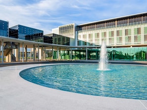 Un edificio moderno con una fuente central y un paseo techado.