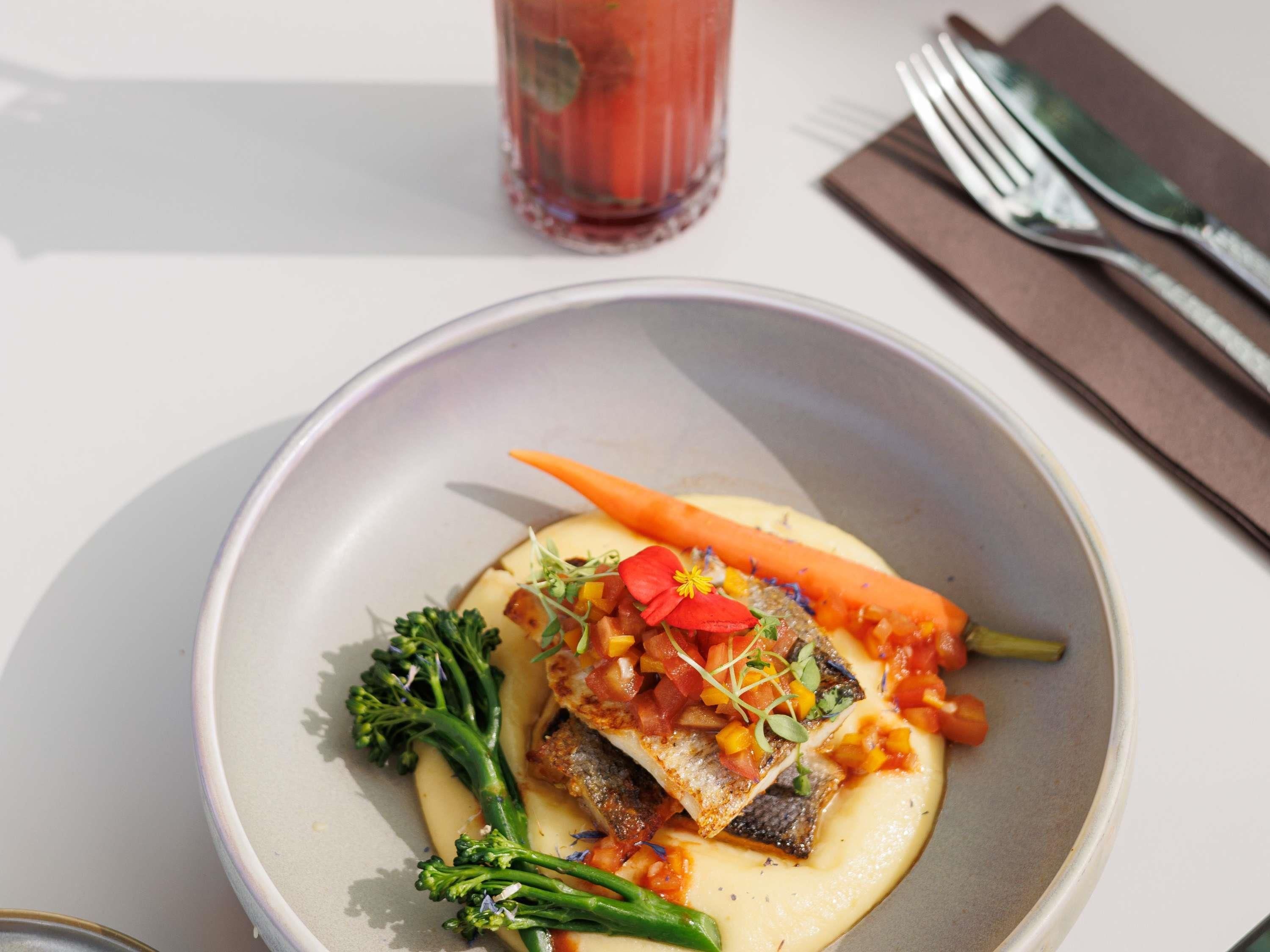 Un plato de comida con pescado, verduras y salsa.