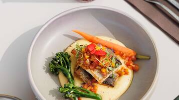 Un plato de comida con pescado, verduras y salsa.
