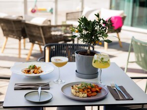 A table set for two with plates of food, a drink, and a potted plant. - Mercure Tallinn (Tallinn)