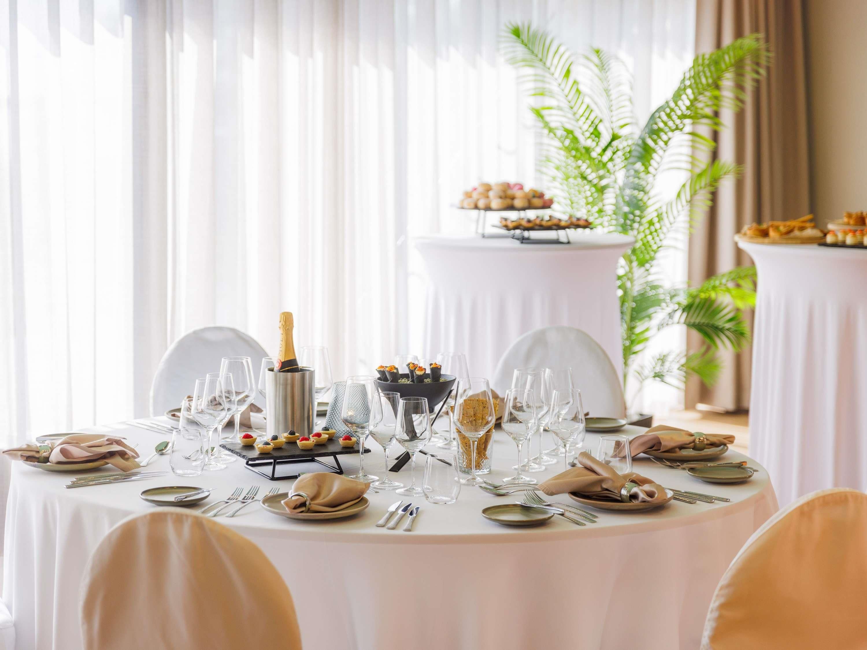 Mesa redonda para comedor dispuesta para un evento formal, con varias copas, platos y una botella de champán.