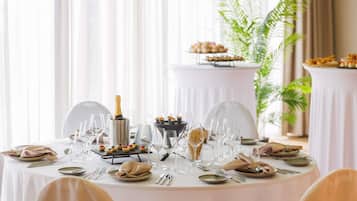 Mesa redonda para comedor dispuesta para un evento formal, con varias copas, platos y una botella de champán.