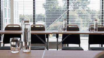 A modern dining area with tables, chairs, and a view of trees through large windows.