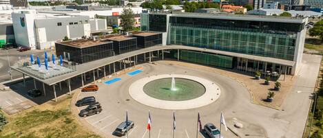 A modern building with a central courtyard, parking area, and surrounding greenery.