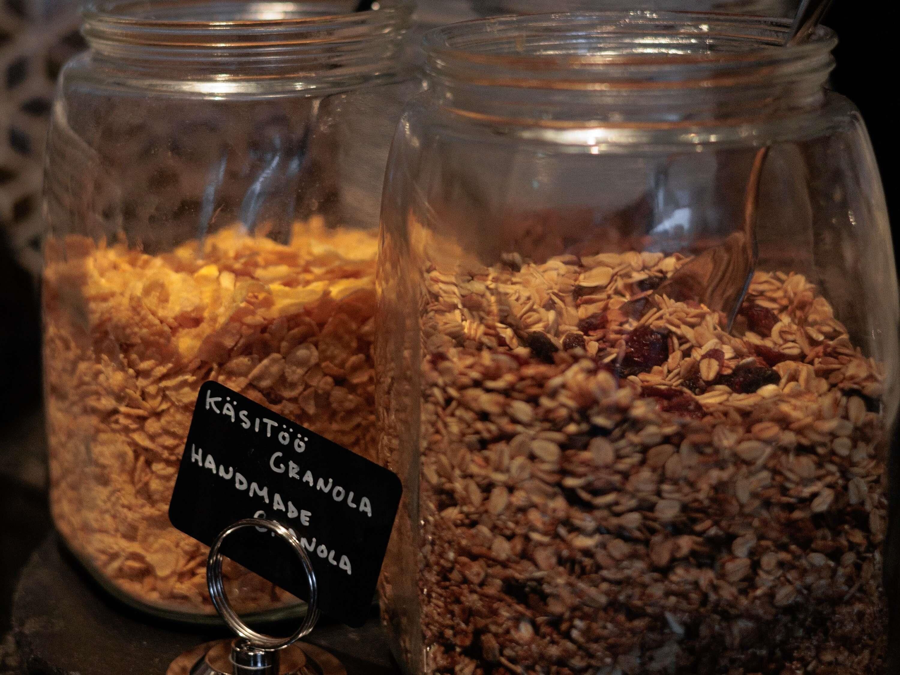 Dos frascos de vidrio llenos de granola, uno etiquetado 'KASITÖÖ HANDMADE GRANOLA' y el otro con una etiqueta similar.