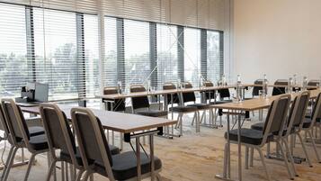 A conference room with a long table, multiple chairs, and a computer on the left.