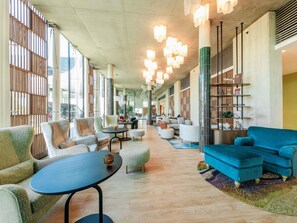 A spacious lobby with modern furniture, large windows, and a central seating area.