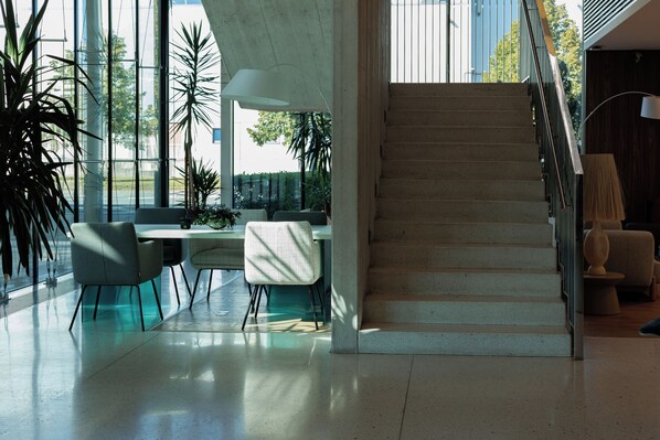 A modern interior with a staircase, a dining area with chairs, and large windows. - Mercure Tallinn (Tallinn)