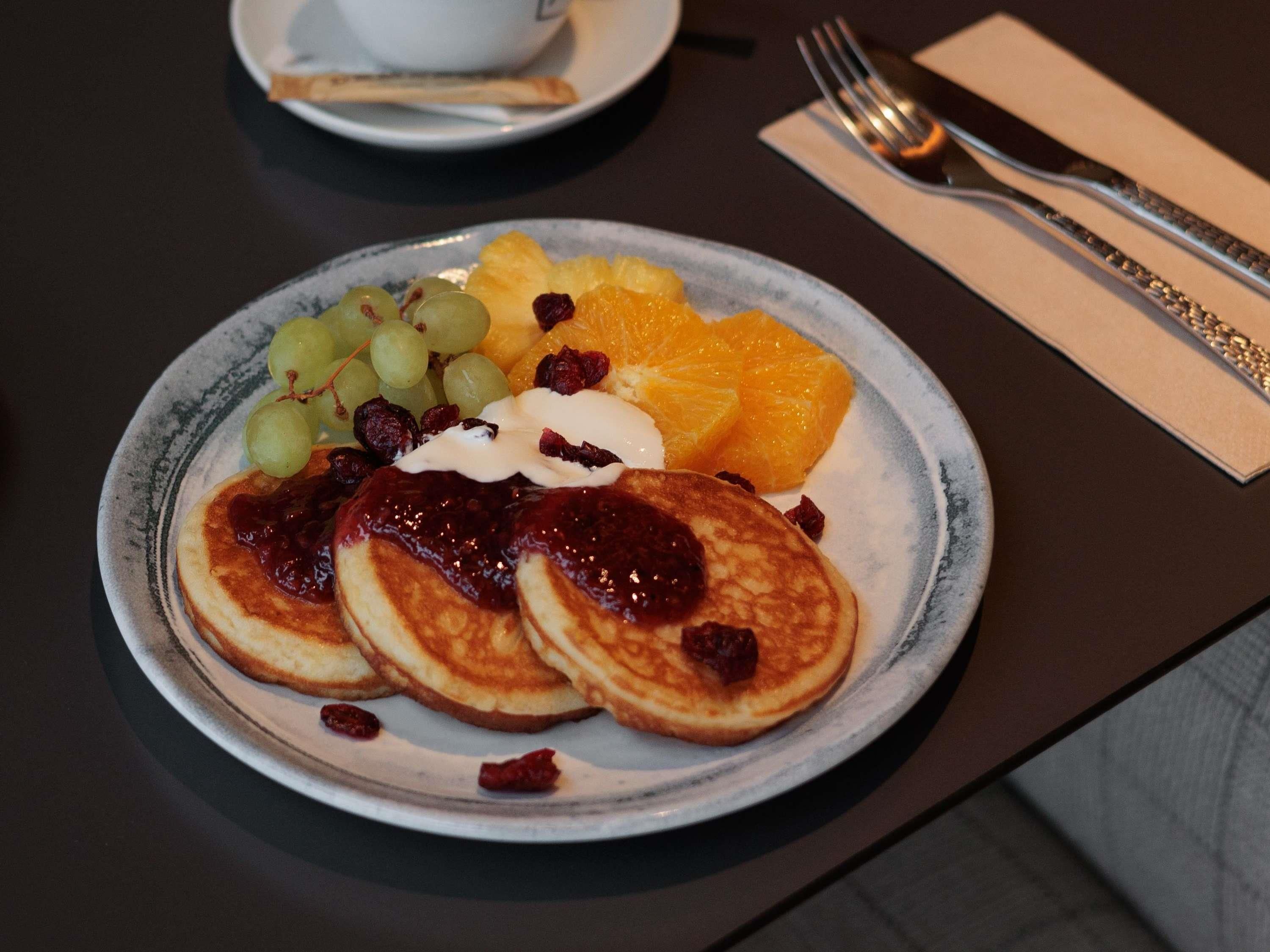 Un plato de tortitas con fruta y crema sobre una mesa.