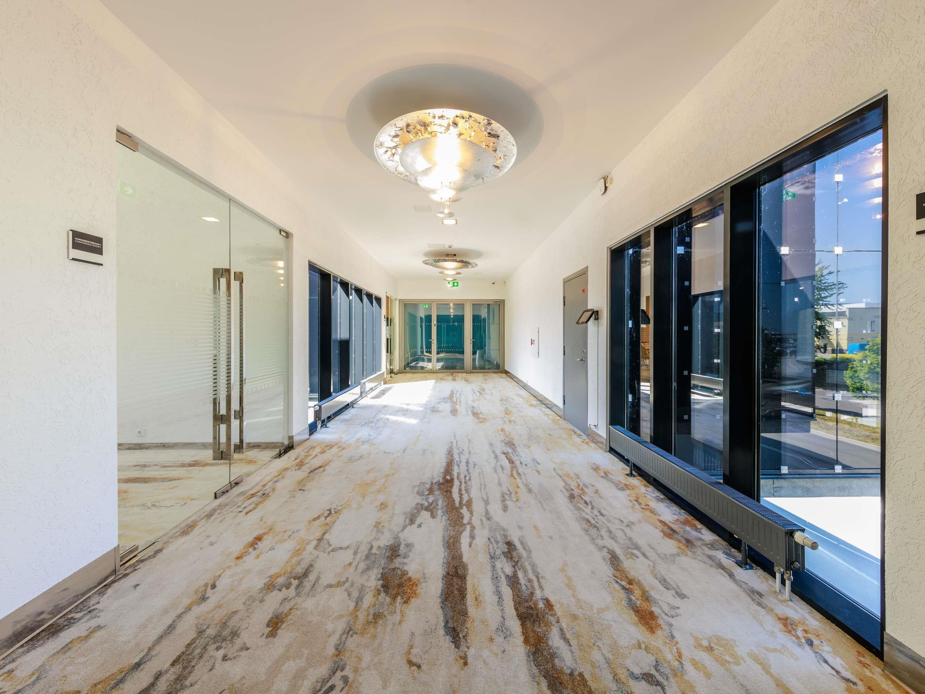 A hallway with a marble floor, glass doors, and a ceiling light fixture.