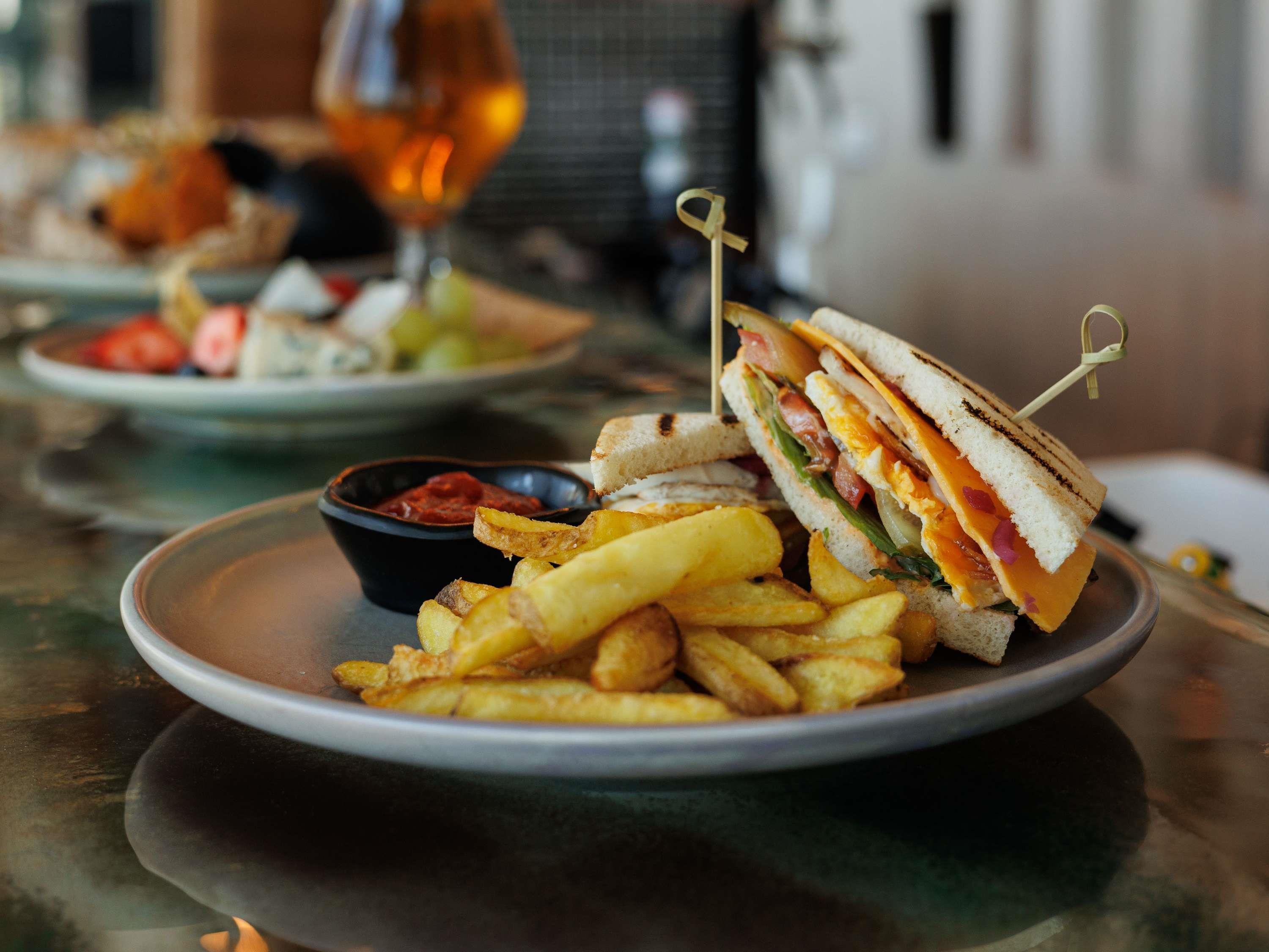 Un plato con un sándwich, papas fritas y un recipiente pequeño de kétchup.