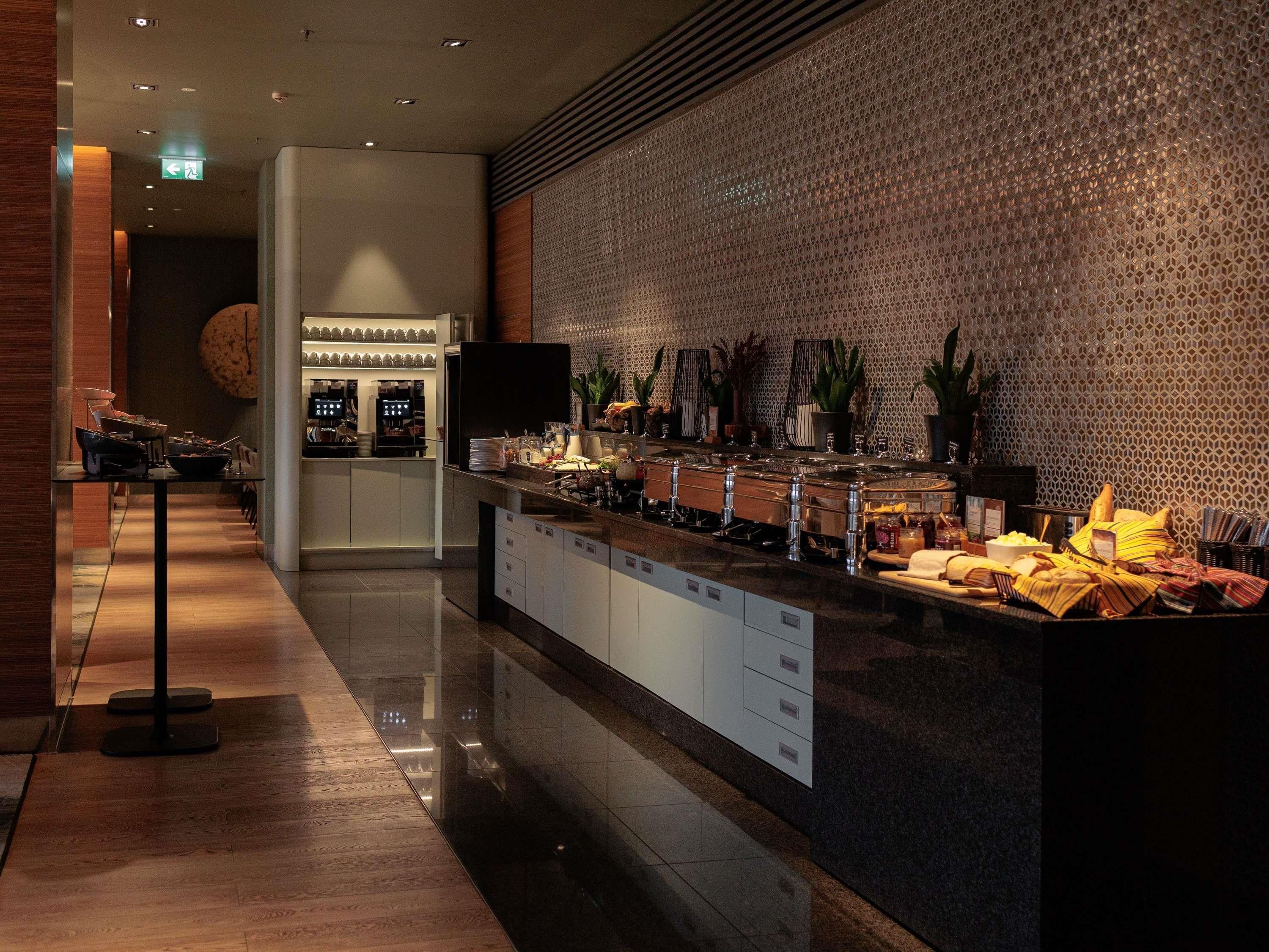 Um saguão de hotel moderno com área de buffet, balcão de recepção e parede estampada.