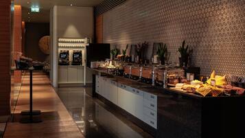 Um saguão de hotel moderno com área de buffet, balcão de recepção e parede estampada.