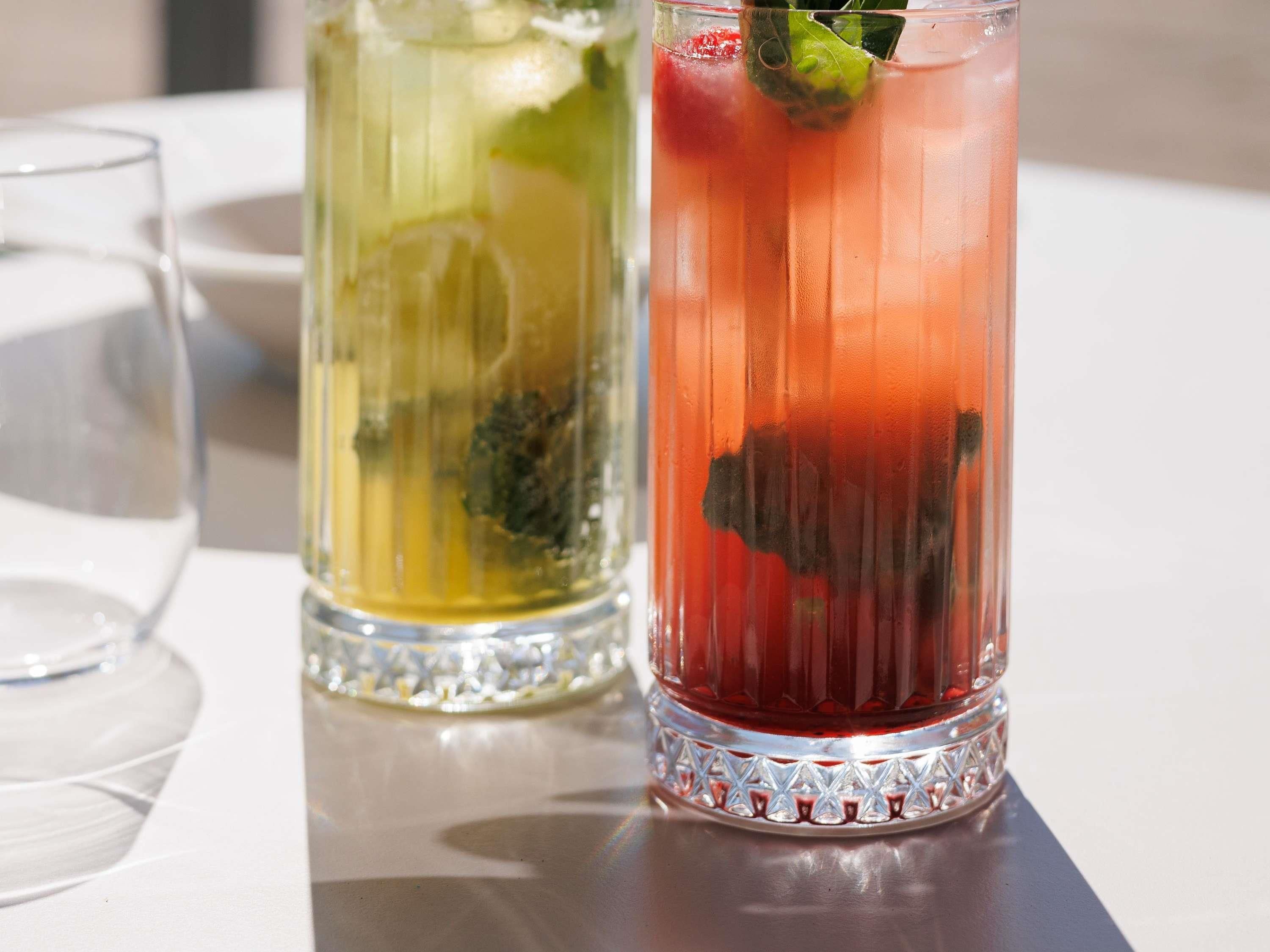 Two glasses of beverages on a table.