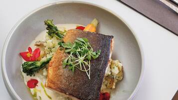 A plate of food with a fish, vegetables, and sauce.
