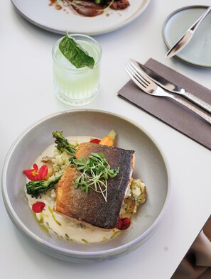 A plate of food with a fish, vegetables, and sauce. - Mercure Tallinn (Tallinn)