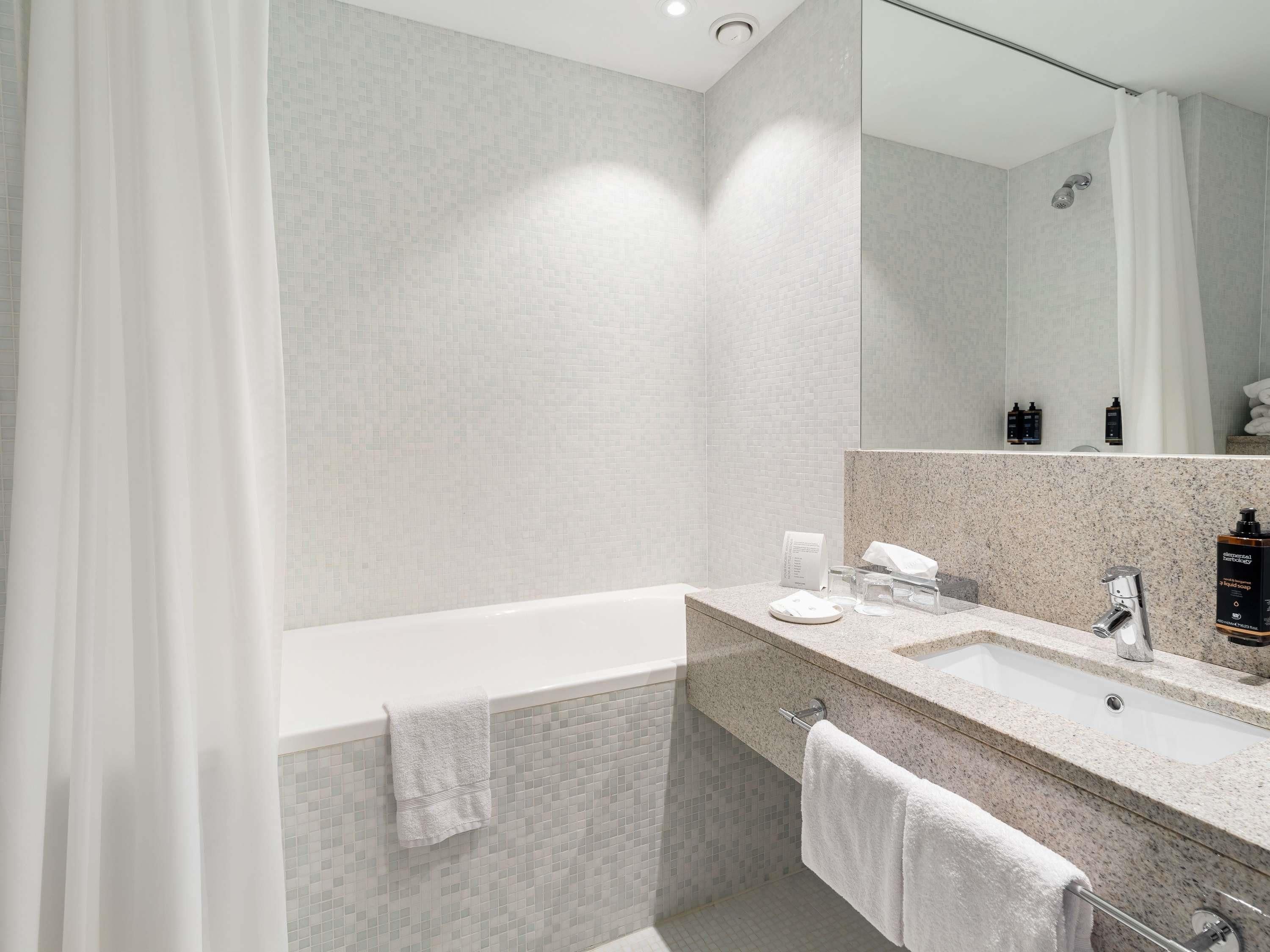 A modern bathroom with a bathtub, a sink, and a mirror.