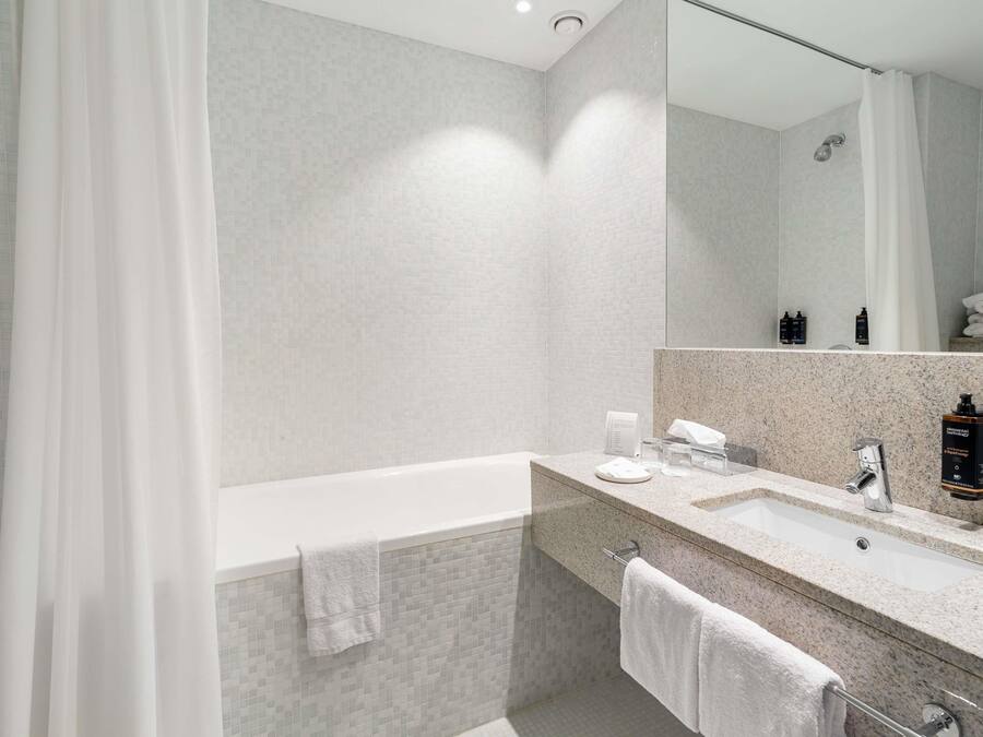 A modern bathroom with a bathtub, a sink, and a mirror.