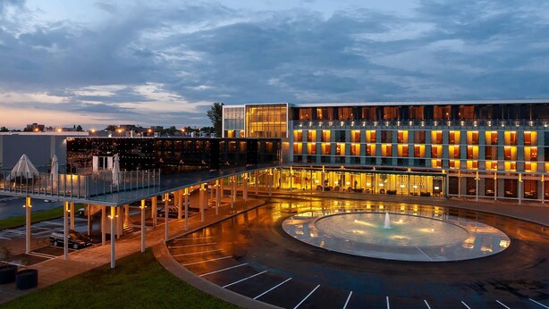 A modern hotel with a spacious outdoor area featuring a circular water feature and a covered walkway. - Mercure Tallinn (Tallinn)