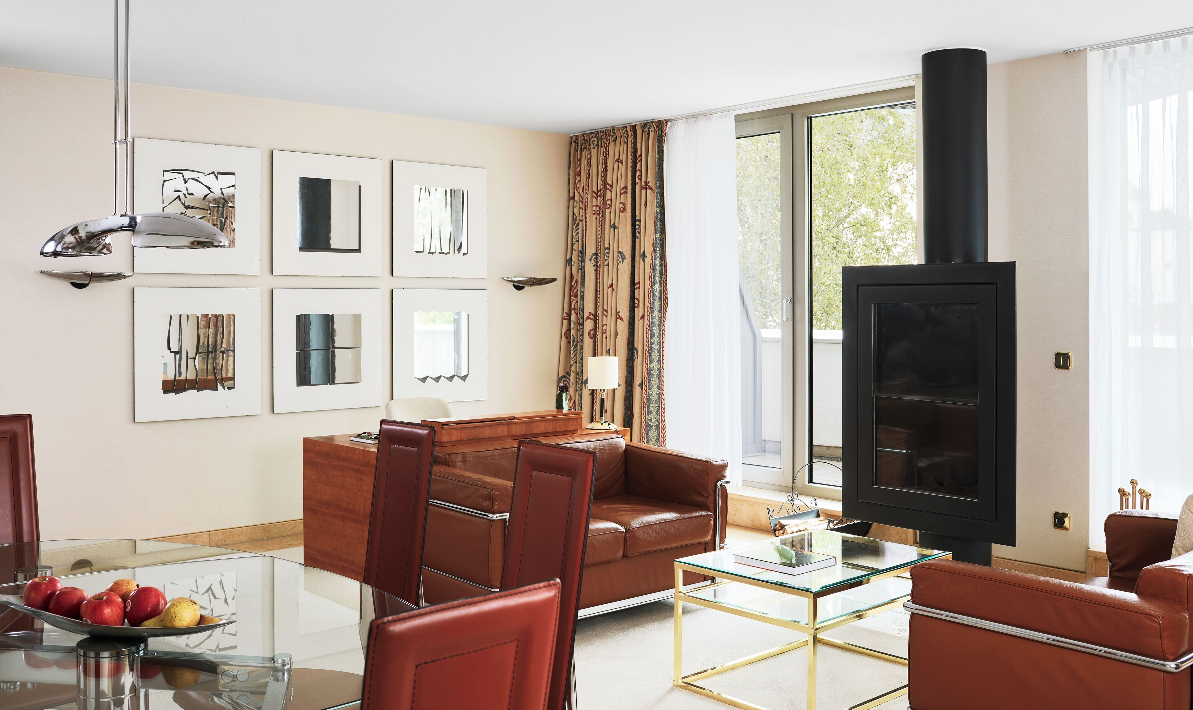 A living room with a sofa, a glass coffee table, a fireplace, and framed artwork on the wall.