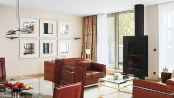 A living room with a sofa, a glass coffee table, a fireplace, and framed artwork on the wall.