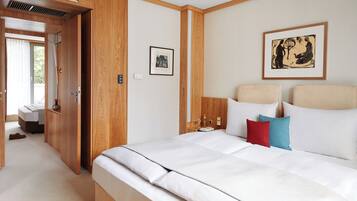 A hotel room with a bed, a bedside table, a mirror, a framed picture, and a window.