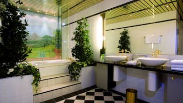 A modern bathroom with two sinks, a large mirror, and decorative plants.