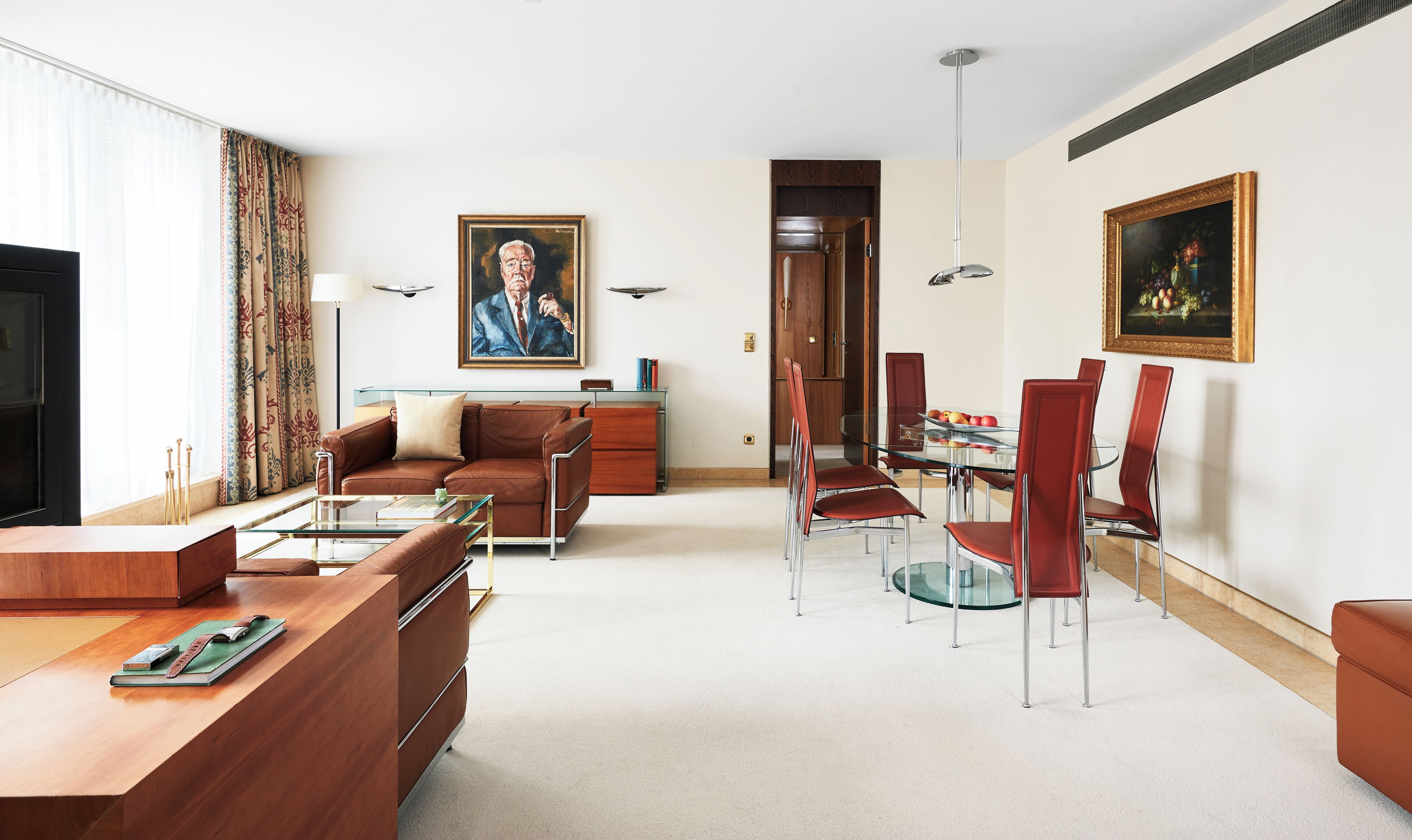 Ein modernes Wohnzimmer mit Sofa, Couchtisch und Essbereich mit Stühlen und einem Glastisch.