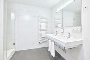 A modern bathroom with a glass shower enclosure, a double sink vanity, and a large mirror.