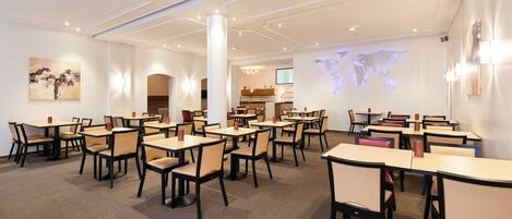 A conference room with tables and chairs, a world map projection on the wall, and a staircase in the background.