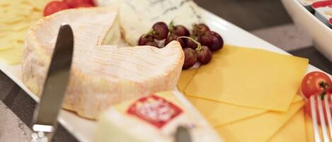 Una tabla de quesos con diferentes tipos de queso, uvas y un cuchillo.