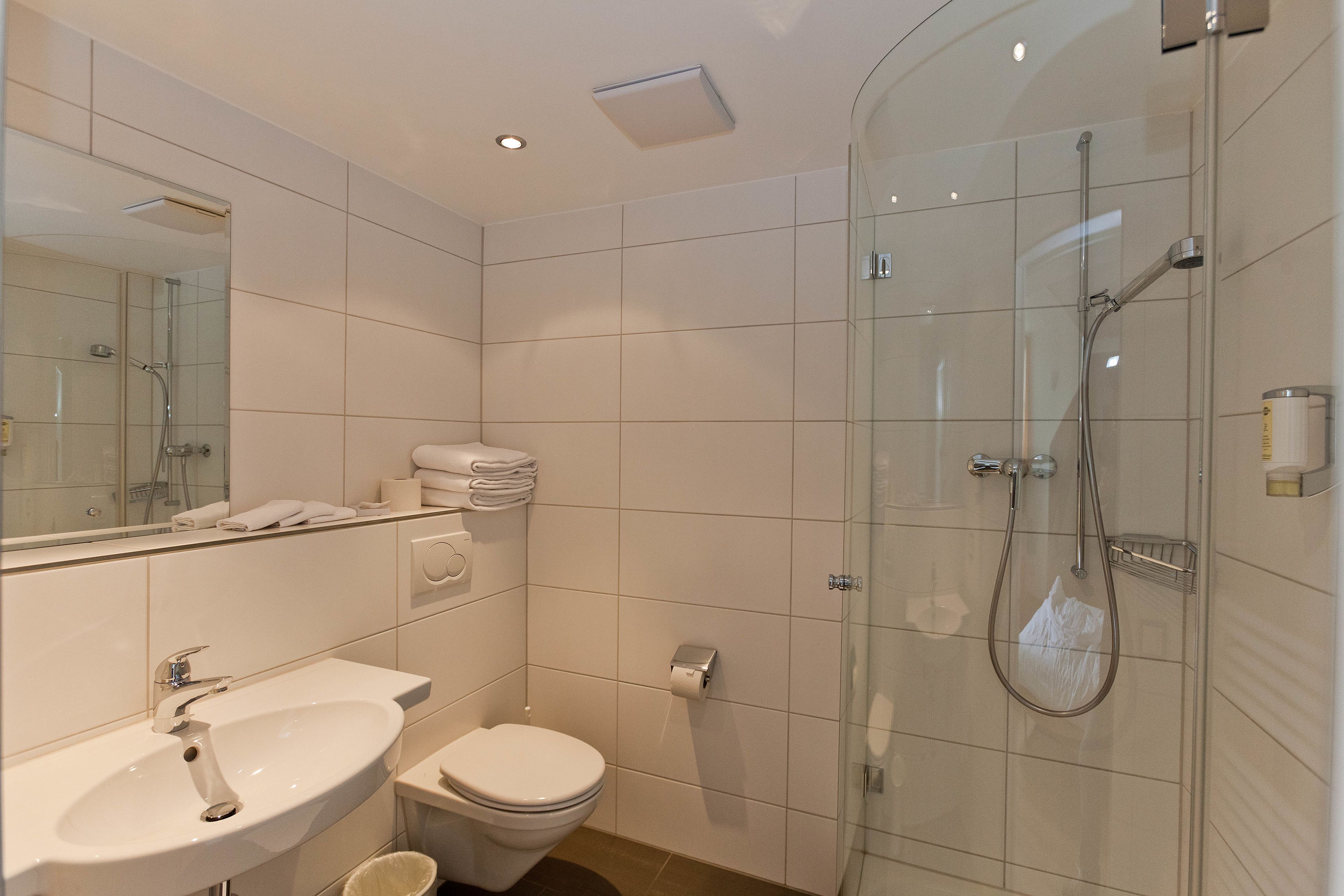 Un bany modern amb dutxa envidriada, un lavabo i un vàter.