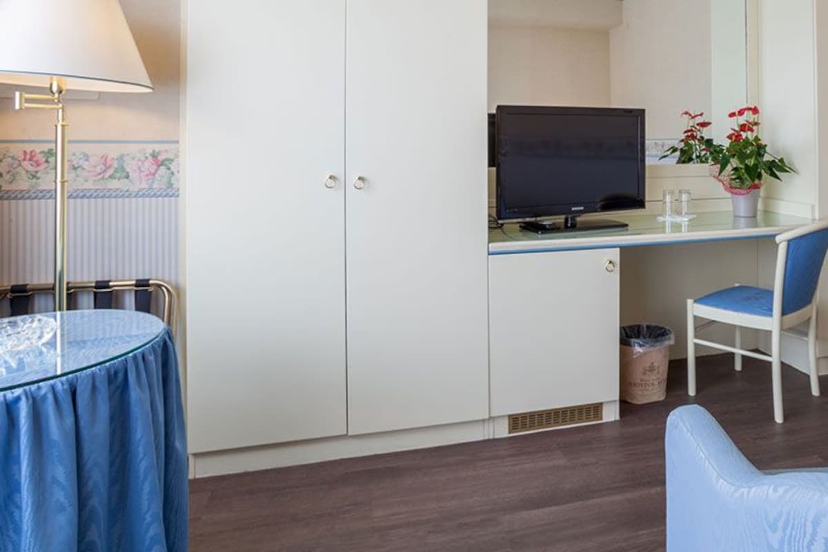 Une pièce de taille modeste comprenant un bureau, une chaise, un téléviseur et un coin salon.