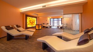 Une salle de spa dotée de plusieurs fauteuils inclinables, d’une cheminée fixée au mur et de grandes fenêtres laissant entrer la lumière naturelle.