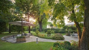 Un espace patio aménagé dans le jardin, avec des sièges extérieurs et un chemin en pierre.