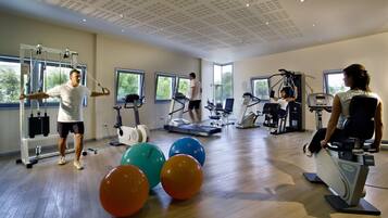 Een ruime fitnessruimte met loopbanden, elastiekballen en krachtapparaten.
