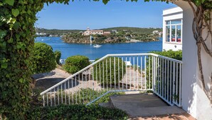 Vista costera con un edificio blanco, una escalera y un mar azul transparente.