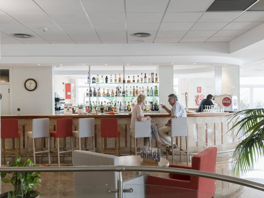 A bar area with seating and a variety of liquor bottles on shelves.