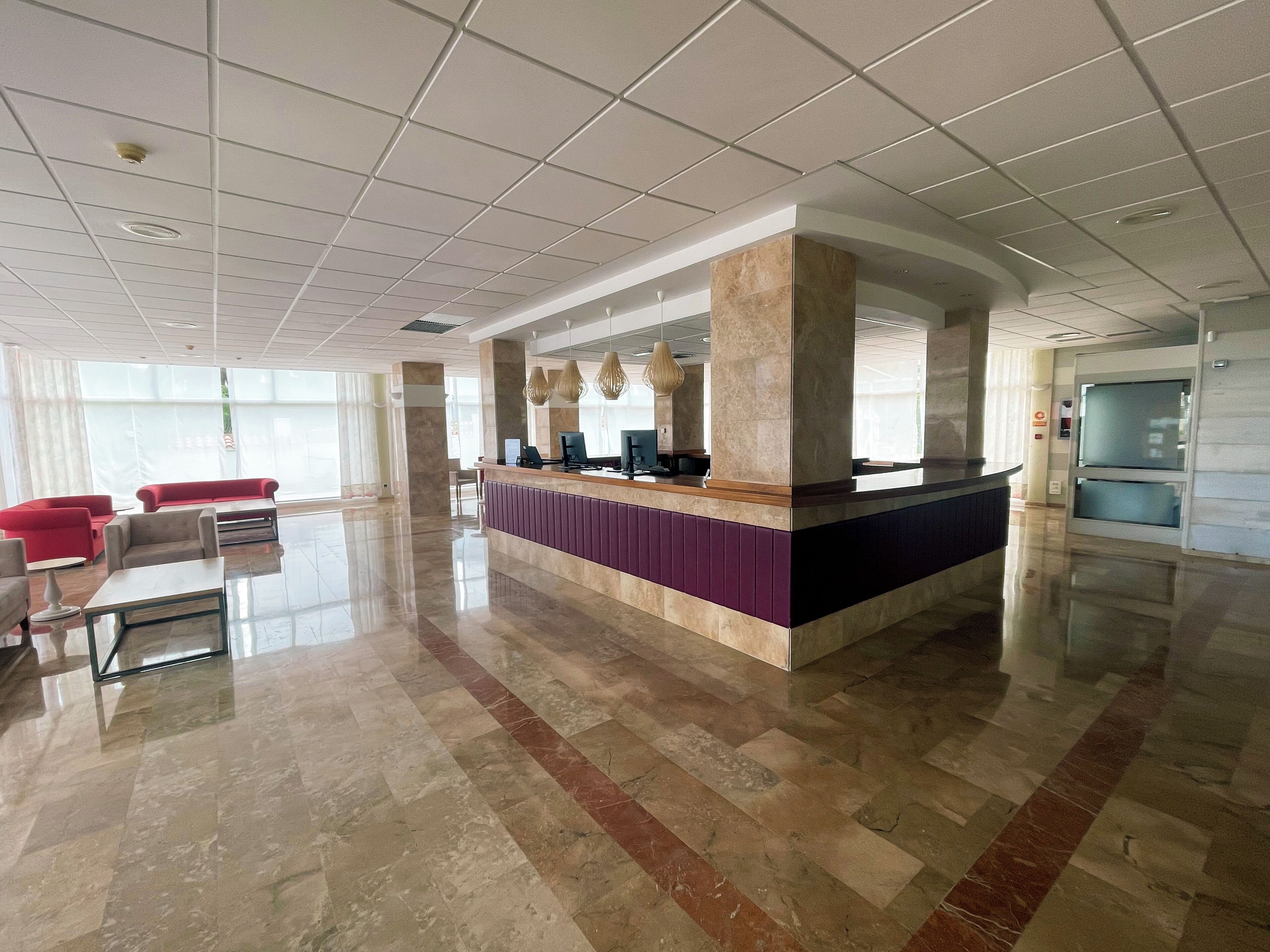 A spacious lobby with a reception desk, seating area, and large windows.